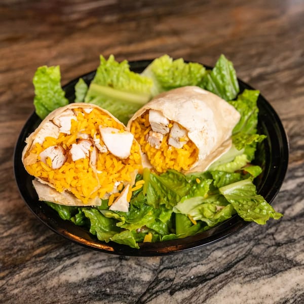 Two grilled chicken and yellow rice burritos, cut in half, served on a bed of fresh lettuce.