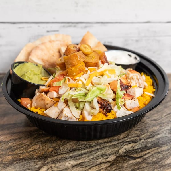 Grilled chicken bowl with yellow rice, lettuce, tomatoes, cheese, plantains, guacamole, and pita bread.