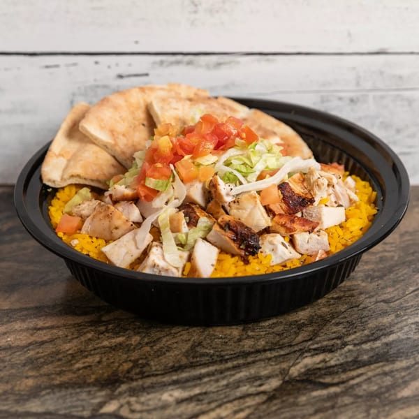 Grilled chicken and yellow rice bowl with pita bread, lettuce, and diced tomatoes.